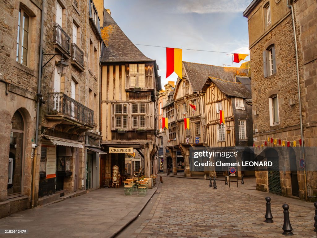 View of a beautiful cobblestone square in the medieval old town of Dinan at sunset with traditional Breton half-timbered houses decorared with wooden beams and arcades, Cotes-d'Armor - Bretagne (Brittany) - Western France.
