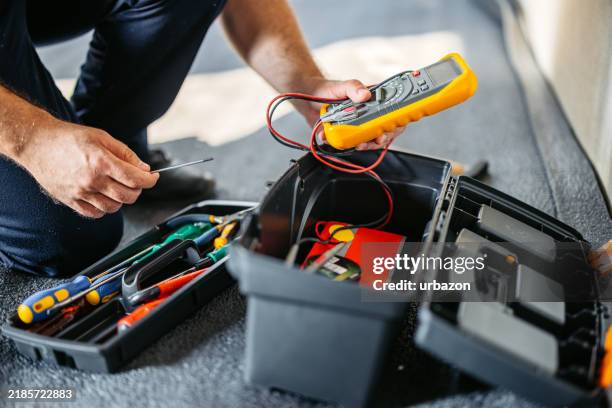 electrician holding a wire tracer to check the cables in an empty apartment under renovation - elétrico imagens e fotografias de stock