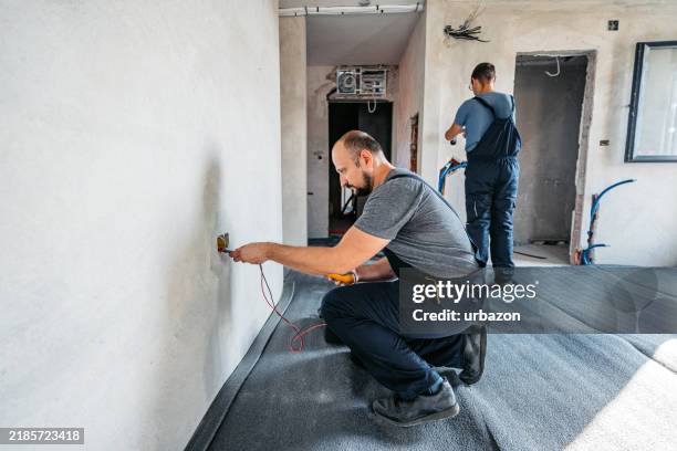 two electricians checking the electric cables with a wire tracer in an empty apartment under renovation - plug socket stock pictures, royalty-free photos & images