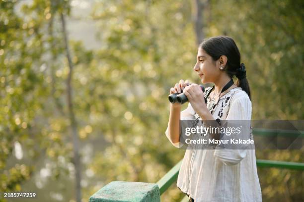 tourist girl spotting wild animals using binoculars standing on the watchtower in satkosia tiger reserve in odisha, india - bird watching stock pictures, royalty-free photos & images