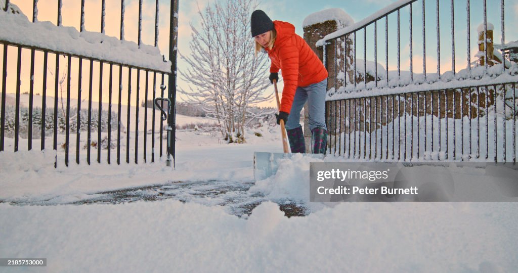 Senior woman clearing snow
