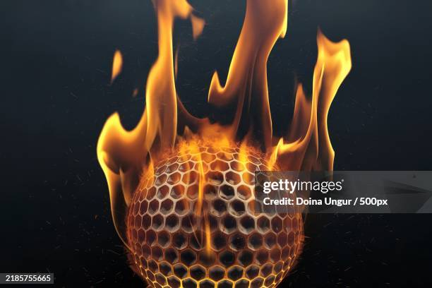 a flaming golf ball with a honeycomb texture against a dark background - fireball stock pictures, royalty-free photos & images