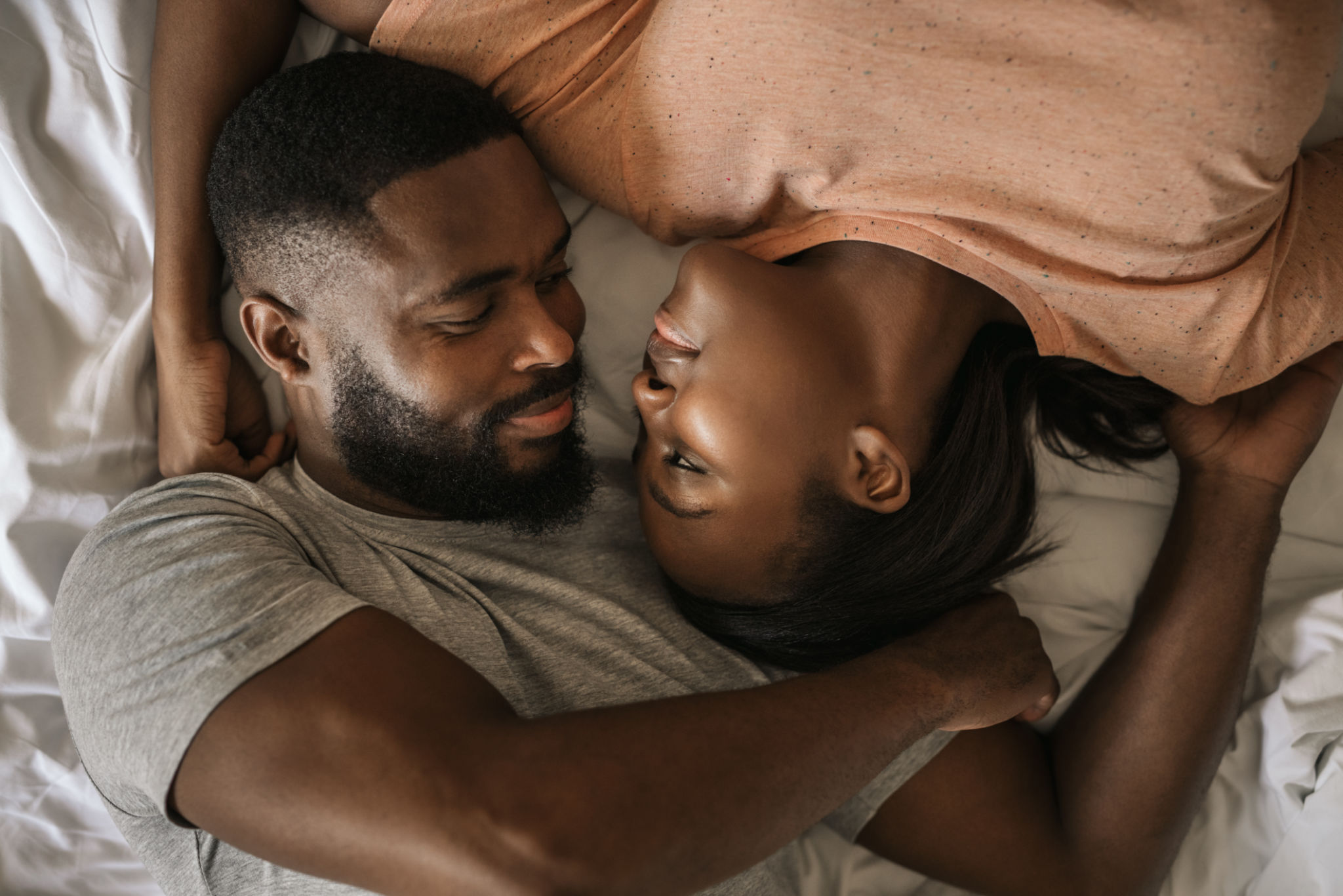 Loving African American couple looking at each other in bed Loving African American couple looking at each other in bed
