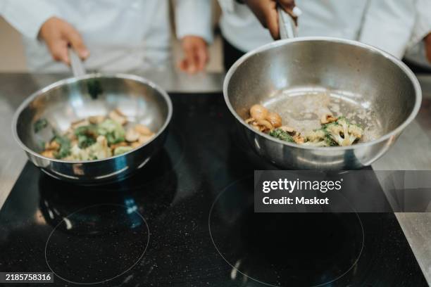 cropped of chefs preparing food in saucepan - placa de fogão vitrocerâmica imagens e fotografias de stock