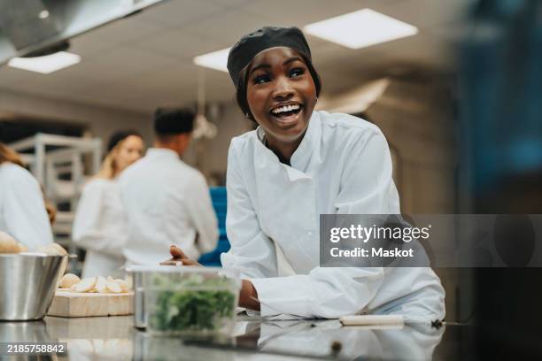 cheerful female trainee leaning on kitchen counter - primo lavoro foto e immagini stock