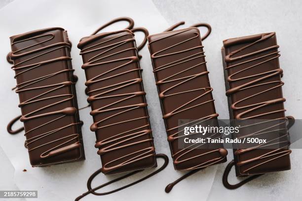 chocolate-covered long,slender bars with a smooth chocolate exterior and a drizzle of chocolate on top - chocolate drizzle stock pictures, royalty-free photos & images