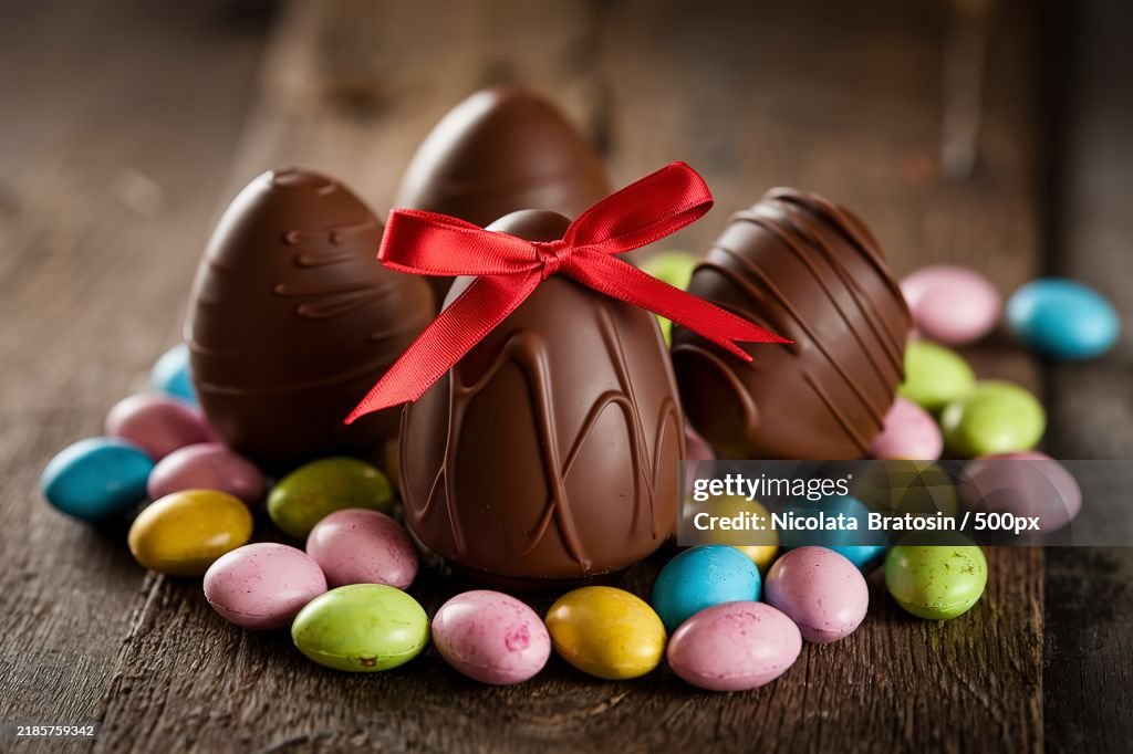 A photo of a rustic wooden surface with several chocolate Easter eggs placed on it