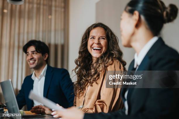happy mature businesswoman sitting amidst male and female colleague at office - arbeitskollege stock-fotos und bilder