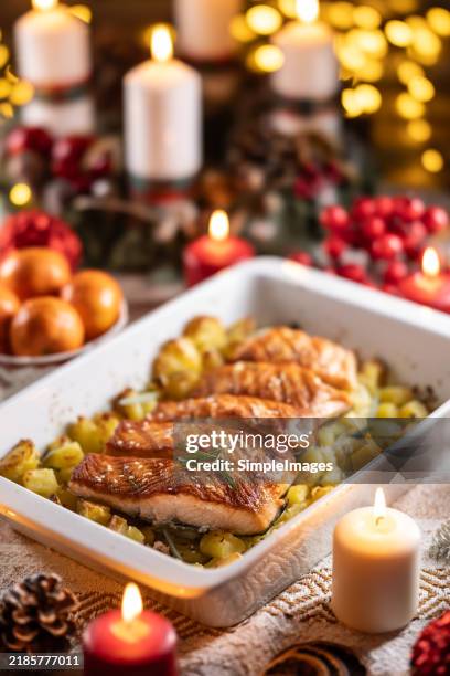 christmas dinner of salmon fish with potatoes in a baking dish with festive decoration of an advent wreath and burning candles - neue kartoffel gekocht stock-fotos und bilder