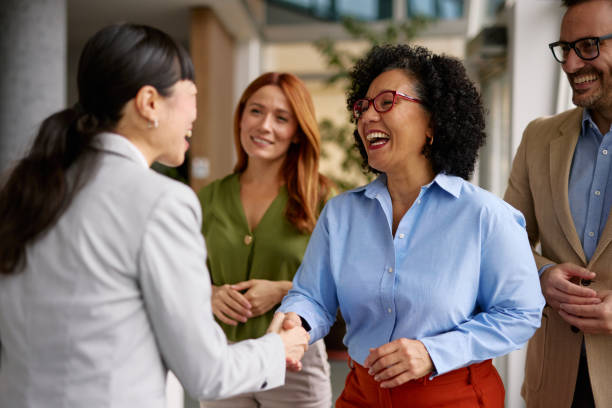 diverse business colleagues shaking hands in a modern office - communication stock pictures, royalty-free photos & images