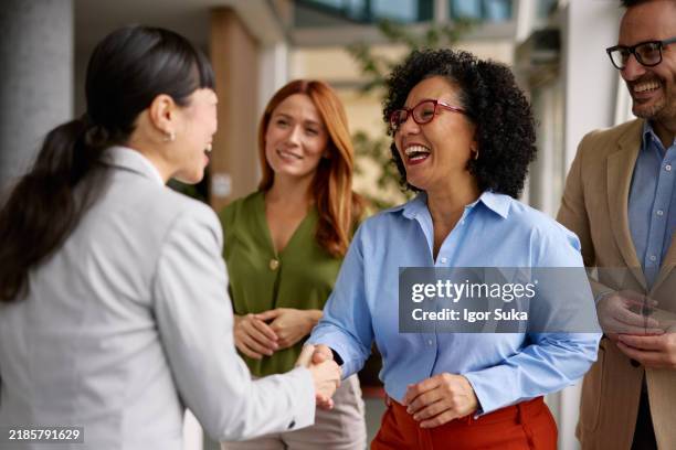 diverse business colleagues shaking hands in a modern office - community leader stock pictures, royalty-free photos & images