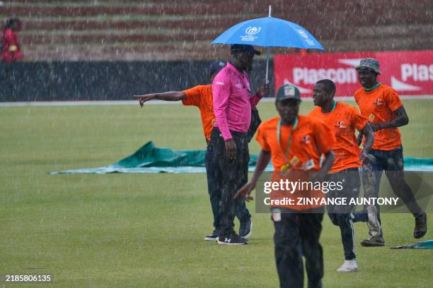An umpire oversees how groundmen get ready to cover the wicket from the rain during the 1st ODI between Zimbabwe and Pakistan at Queens Sports Club...