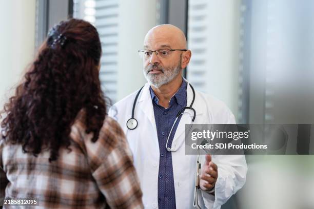 seriöser arzt spricht mit der mutter des patienten - kardiologe stock-fotos und bilder