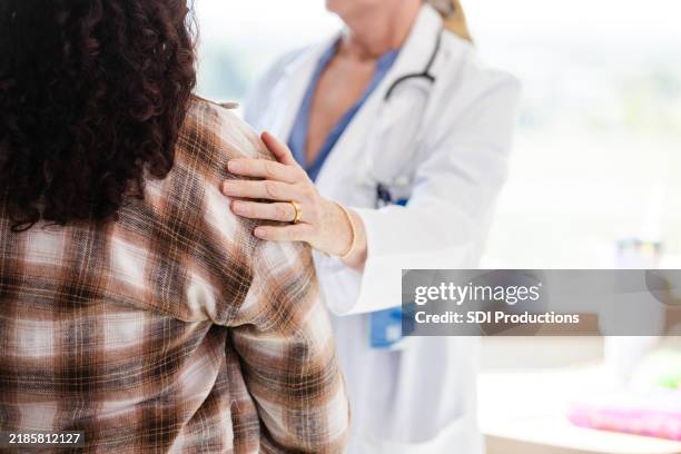 ein nicht wiederzuerkennender arzt tröstet die mutter der patientin - schlechte nachricht stock-fotos und bilder