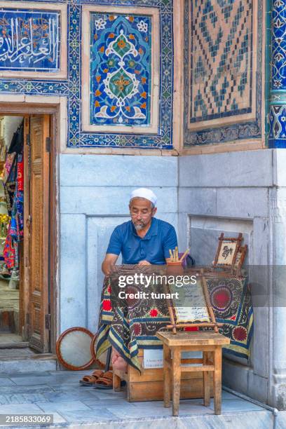 usbekischer ladenbesitzer aus samarkand sitzt vor seinem laden - samarkand stock-fotos und bilder