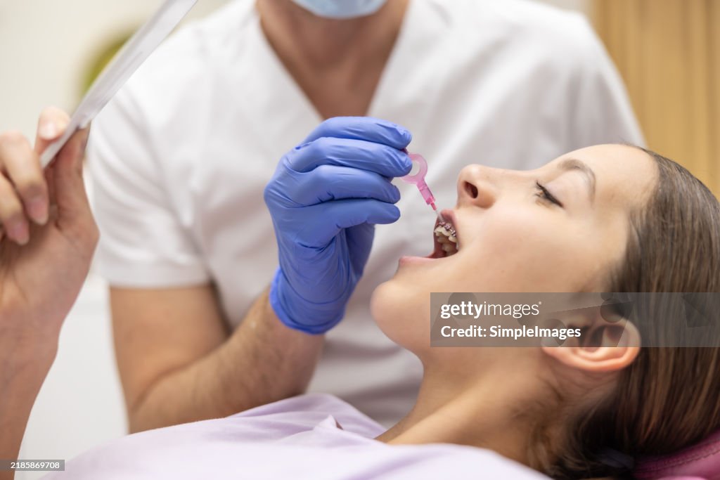 Dentist shows teenage girl how to clean her braces with an interdental brush