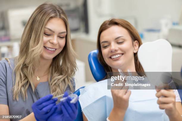 a dental expert shows a young patient with beautiful teeth how to use invisiline braces - dentalhygieniker stock-fotos und bilder