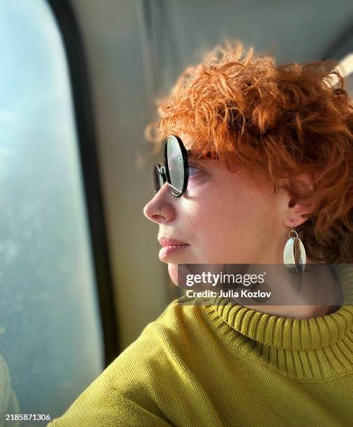 47-years-old woman commuting by train looking out window during during journey from new jersey to nyc. - earring stock pictures, royalty-free photos & images