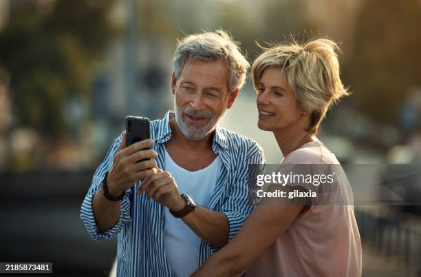 middle aged couple walking in a city street. - ouder-volwassenen-koppel stockfoto's en -beelden