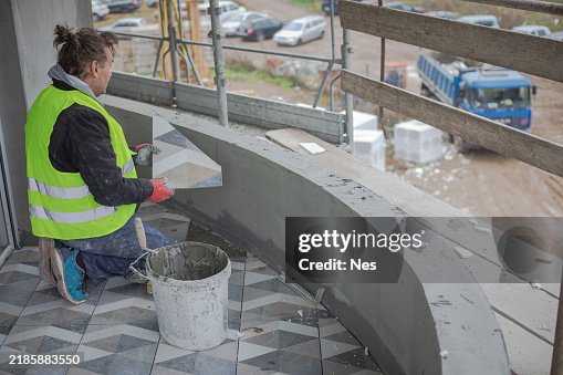 Construction site, construction worker installing ceramic tiles Construction site, construction worker installing ceramic tiles