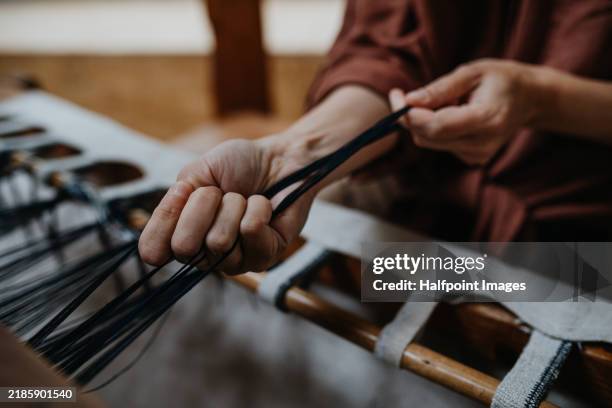 close up of woman’s hand working with wooden loom, weaving handmade product, using eco-friendly materials. weaving small business for female business owner. circular economy concept. - kreislaufwirtschaft stock-fotos und bilder