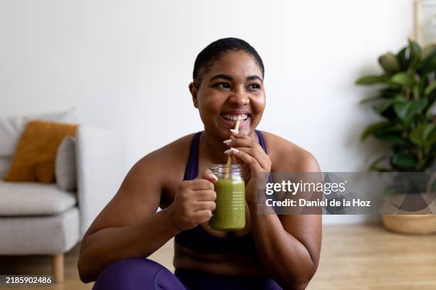 young woman enjoying healthy green smoothie after workout - smoothie stock pictures, royalty-free photos & images