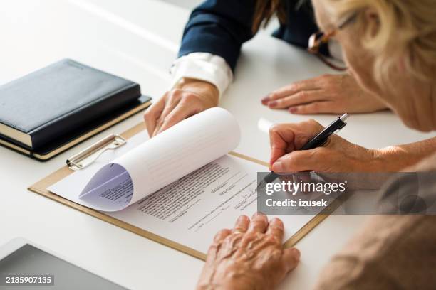 senior woman signing the will with lawyer - erfenis stockfoto's en -beelden