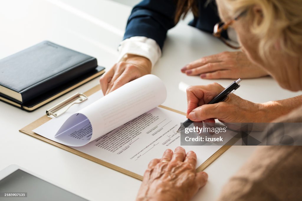 Mulher sênior assinando o testamento com advogado