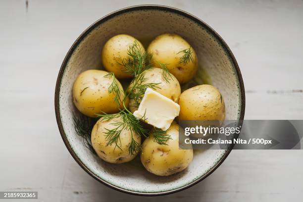 a photo of a dish with early boiled potatoes,butter,and fresh dill - gekookte aardappel stockfoto's en -beelden