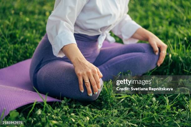 serene woman enjoying a peaceful yoga session on a mat in nature, finding balance and mindfulness - cross legged stock pictures, royalty-free photos & images