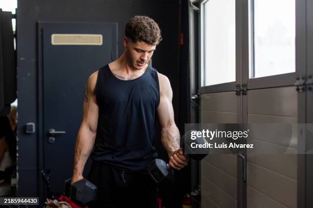 focused athlete lifting dumbbells in gym - bicep stock pictures, royalty-free photos & images