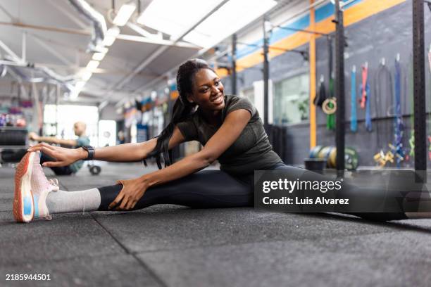 happy young woman stretching leg hamstring at cross training gym - jambes écartées photos et images de collection