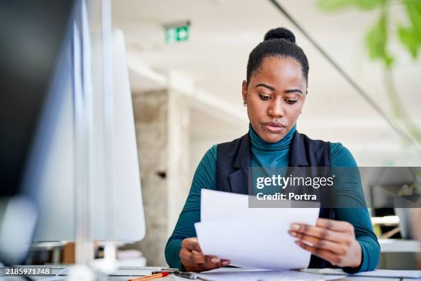une femme d’affaires africaine examinant des documents posée à son bureau - relevé bancaire photos et images de collection