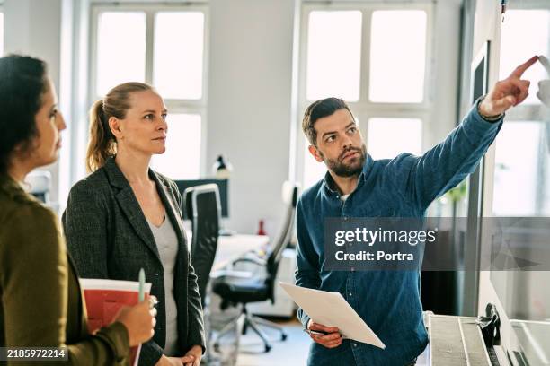 männlicher profi erklärt dem team im büro ein neues projekt über ein whiteboard - digitales marketing stock-fotos und bilder