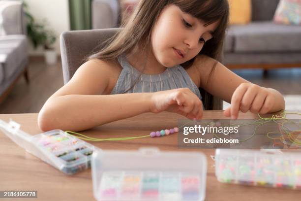 little girl making bead bracelets - manufactured object stock pictures, royalty-free photos & images