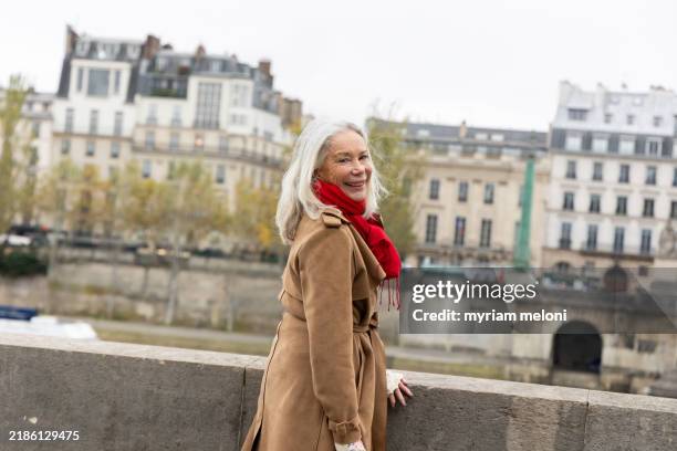portrait of a smiling elegant senior woman with white hair walking through the city - charmant stock-fotos und bilder
