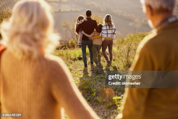 vista trasera de una familia multigeneracional en un día de otoño en una colina. - familia multigeneracional fotografías e imágenes de stock