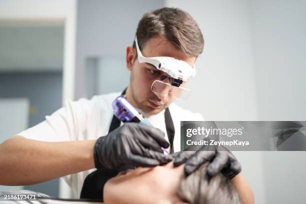 esthéticienne masculine appliquant un maquillage permanent dans un salon de beauté. - maquillage permanent photos et images de collection