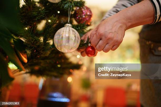 close up to hands hanging knick knacks on christmas tree. - espírito natalino imagens e fotografias de stock
