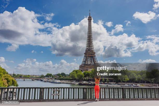 femme active en tenue de sport s’étirant sur le pont sur la seine à paris par une belle journée - joggeuse photos et images de collection