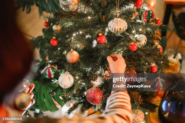 close up to hands hanging knick knacks on christmas tree. - decorating-the-christmas-tree stock pictures, royalty-free photos & images
