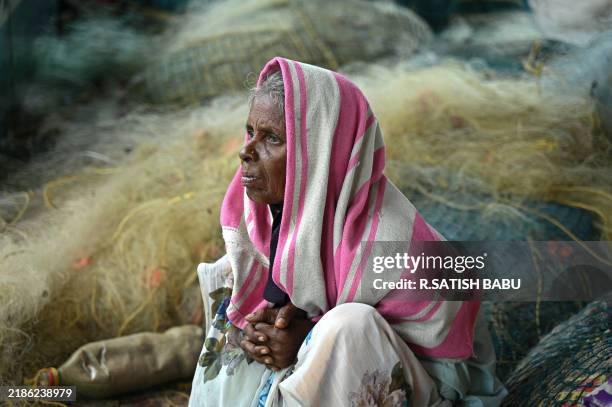 Woman takes shelter from rain at the Kovalam beach on the outskirts of Chennai on November 26, 2024.