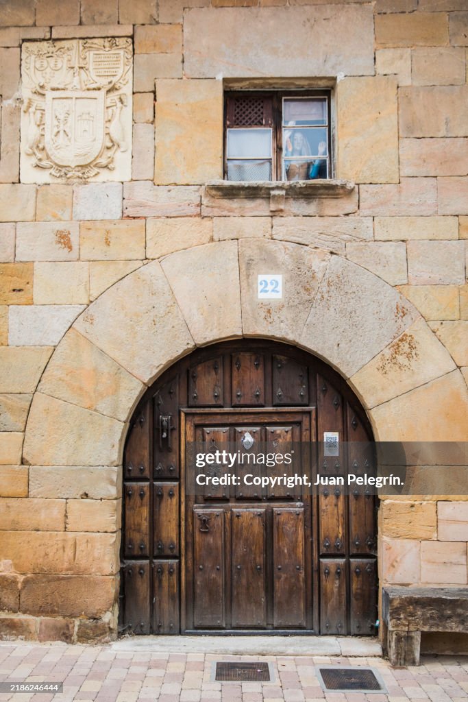 Medieval facade with door, window and coat of arms