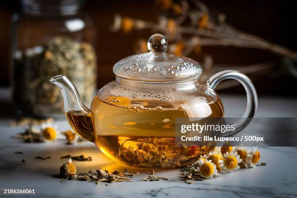 a photo of a glass teapot filled with golden chamomile tea - chamomile stock pictures, royalty-free photos & images