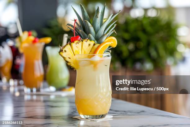 a tropical cocktail with a pink hue,topped with a slice of pineapple and a cherry - essbare verzierung stock-fotos und bilder
