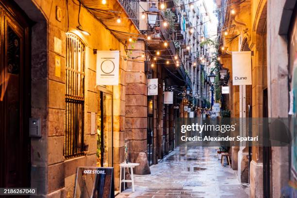 small shops on a narrow alley in el born district, barcelona, spain - gotisches viertel barcelona stock-fotos und bilder