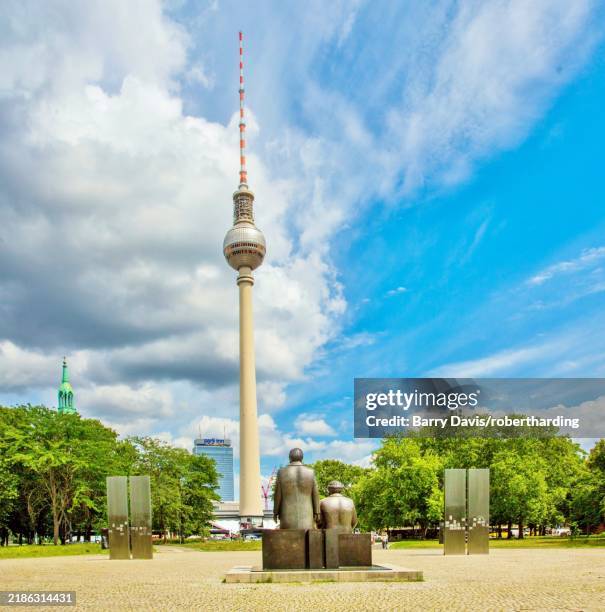 marx and engels statues survey the berlin tv tower (fernsehturm) in marx-engels forum, a public park in the mitte district, central berlin, germany, europe - berliner fernsehturm stock-fotos und bilder