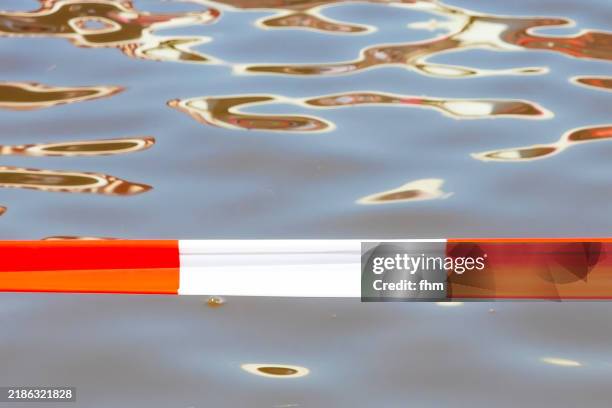 red-/white barricade tape with water in background - barrikade stock-fotos und bilder