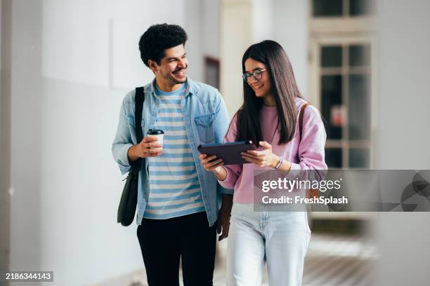 young adults smiling while walking in a bright hallway - study hall stock pictures, royalty-free photos & images