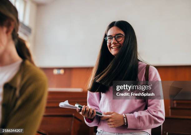 happy student laughing in classroom holding notebooks - person of color stock pictures, royalty-free photos & images